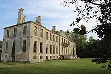 Vue d'un château ayant perdu son toit entouré d'une pelouse et d'arbres