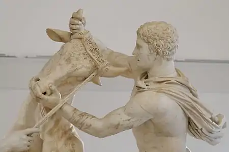 Vue détaillée de la tête du taureau et de la figure d'homme qui la tient par les cornes.