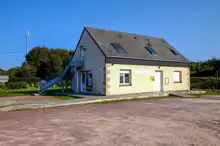 Une maison sur un parking. Un escalier en colimaçon extérieur permet d'accéder à l'étage