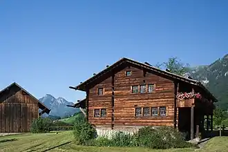 Photographie d'un chalet avec paysage alpin et fond de ciel bleu.
