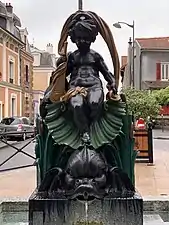 Fontaine. Chérubin de bronze assis dans une coquille saint Jacques, surmonte un poisson. Voûte de drap noué par une rosette sur la cuisse et la coquille.