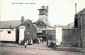 Carte postale noir et blanc de bâtiments industriels en briques surmontés d'une tour en bois.