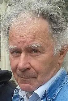 Photographié de face et en plan serré, François Joxe, vêtu d'une chemise blanche et d'une veste de jeans bleu clair ; il a un léger sourire teinté d'ironie.