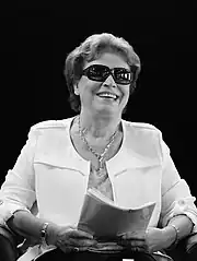 Photographie noir et blanc. Femme assise à lunettes de soleil.