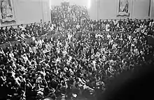 Photographie en noir et blanc d'une foule envahissant un amphithéâtre.