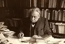 Photographie en noir et blanc d'un homme travaillant à son bureau.