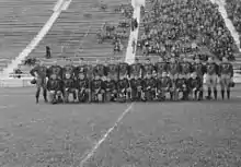 Les joueurs des Indians posant sur la pelouse de leur stade sur deux rangées. En arrière-plan, les gradins avec des spectateurs.