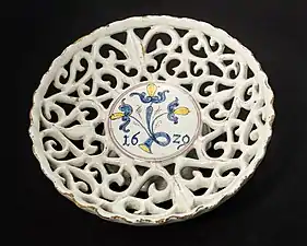 Coupe à pied (environ 7 cm de haut, 20 cm de diamètre), en faïence ajourée à glaçure au dioxyde d'étain en forme de vigne, produite en 1629 dans l'ouest de la Slovaquie/Moravie (peut-être à Sobotište), l'une des plus anciennes œuvres connues des Haban (de).