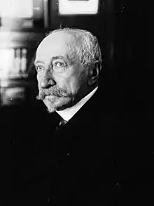 Photographie en noir et blanc d'un vieil homme atteint de calvitie, portant moustaches et barbe.