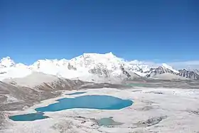 Vue du versant ouest du Gangkhar Puensum depuis le Gophu La, avec à gauche du sommet la longue arête horizontale qui mène à son sommet secondaire, le Liankang Kangri (7 535 m).