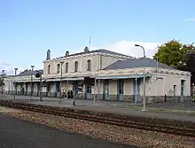 Une gare vue du côté opposée de la voie ferrée.