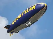 dirigeable gris et bleu avec la marque Goodyear en jaune.