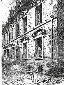 Dessin en noir et blanc d'une rue pavée bordée d'un immeuble à plusieurs étages.