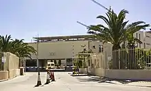 Un bâtiment blanc à toit plat, protégé par des grilles