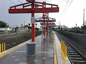 Vue du quai central de la station. L'œuvre, des totems de couleur rouge, est visible.