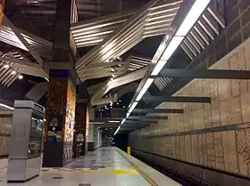 Vue en contre-plongée du quai. On voit des sortes de mosaïques sur le mur.