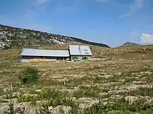 Bergerie isolée dans un terrain de montagne mi-rocheux mi-herbeux.