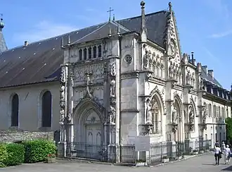 Photo de la façade occidentale (chapelle de Belley ou d'Estavayer) de l'église abbatiale, achevée en 1837. À gauche, l'ancienne porte créée par Claude d'Estavayer.
