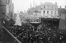 Photo en noir et blanc d'une foule entourant une imposante statue blanche