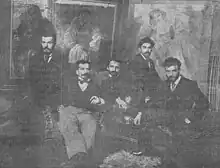 Photographie en noir et blanc de groupe de cinq hommes assis posant pour l'appareil photo.