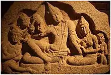 5 personnages assis. Au centre le roi, entouré de son épouse et d'un enfant et de deux serviteurs de l'autre côté.