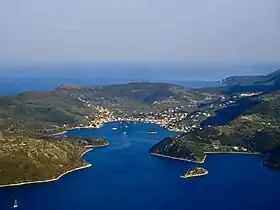 Bourg niché dans l'anse d'un port et sur les flancs d'une île volcanique, prise d'avion, ciel bleu