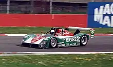 Photographie d'une voiture d'endurance verte, blanche et rouge, vue de trois-quarts gauche, dans son ensemble, sur une piste sèche.
