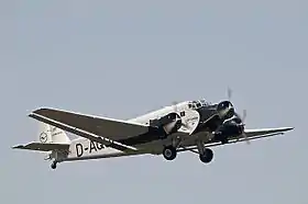 Photographie d'un avion à hélices dans les airs.