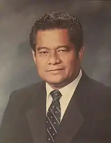 Photo de face d'un homme à la peau mate, en costume.