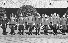 Photo d'un groupe d'hommes en uniforme. Ils sont alignés et posent devant un bâtiment.