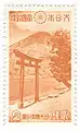 Timbre bicolore orange et blanc montrant une montagne au bord d'un lac, avec au premier plan, un portail traditionnel de sanctuaire shinto.