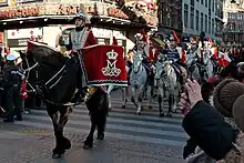 Des militaires danois à cheval, vêtus de rouge et de bleu, lors d'un défilé dans les rues, au milieu de la foule.