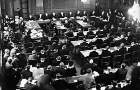 Le Procès en responsabilité de guerre en novembre 1945. Les membres du tribunal sont derrière la table en forme de fer à cheval, devant eux les secrétaires et les sténographes, derrière en trois rangées les accusés et leurs avocats. À gauche, le procureur, les représentants de la Commission de contrôle et des diplomates étrangers, au premier plan le public et les journalistesSoini 1956, p. 181.