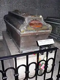 Photographie d'un sarcophage sur un socle en pierre, avec un médaillon le nom de l'empereur