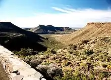 Une vue depuis le sommet du Grand Escarpement près de Beaufort West, en regardant vers le sud, surplombant les plaines du bas-Karoo. On voit les restes du plateau ancien et les sills de dolérite qui surmontent, au loin, les sommets, donnant les structures caractéristiques à sommets plats.