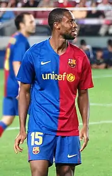 Photographie d'un joueur avec le maillot bleu et rouge de Barcelone, en train de regarder une tribune