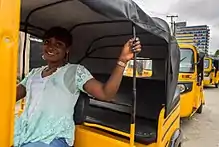 femme au guidon d'un tricycle destiné au transport de passagers