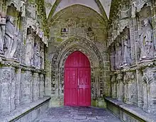 Intérieur du porche. De chaque côté sont alignées les statues des apôtres. Au fond, une porte en tiers-point.