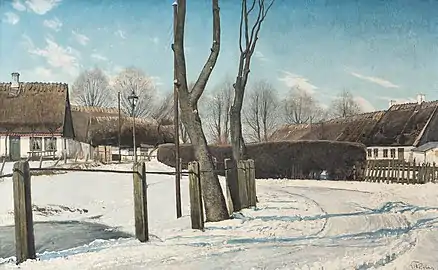 Une route enneigée près d'habitations.