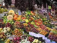 Un étalage de marché, couvert de fruits et légumes.