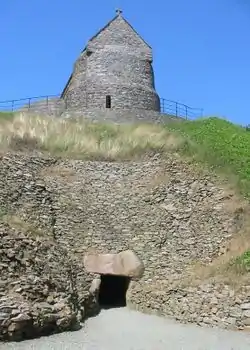 Entrée restaurée de la tombe néolithique de La Hougue Bie. La chapelle repose sur le monticule.