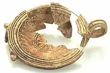 Lampe à huile à réservoir, fragmentaire et de couleur beige - ocre. Un motif floral décore le fond.