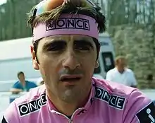 photo couleur d'un sportif à maillot rose marqué ONCE. les mêmes remarques s'appliquent au bandeau tour de tête.