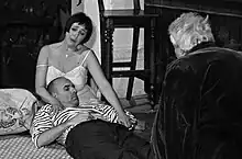 Représentation du Pauvre Matelot (musique de Darius Milhaud, texte de Jean Cocteau, production de l'ARCAL) dans un café du théâtre de La Valette, à Malte. Production par l'ARCAL. Mise en scène Christian Gangneron Piano & direction musicale Stéphane Petitjean. Photo en noir et blanc, où l'on voit de gauche à droite, Jean Delescluse (le matelot), Claudine Le Coz (sa femme), Jean-Baptiste Dumora (son ami)