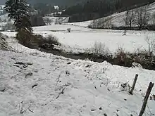 Photographie du ruisseau entre deux champs couverts de neige