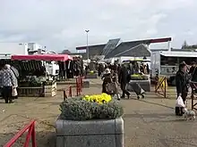 Photographie en couleurs d'un marché en extérieur, une vasque fleurie au premier plan.