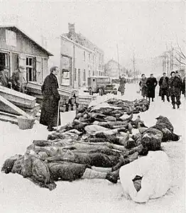 Le père Musty devant les dépouilles des 34 civils.
