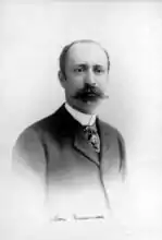 Homme jeune avec mouctache et dégarni.