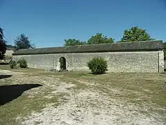 Photographie d'un long mur sans décor percé d'une porte.