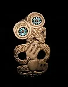 Pendentif hei tiki. Peuple Maori. Os gravé, nacre. H. 10 cm. Nouvelle-Zélande. 1850-1950.